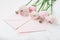 Envelope or letter, paper card and pink ranunculus flowers on white table for greeting on Mother or Woman Day.