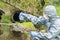 Environmental biologist in a protective suit and mask examines water from the river for viruses