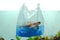 Environmental concept plastic bag holds blurred turtle toy in water