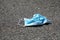 Environmental pollution. Close up of used surgical mask on the asphalt. Disposable face mask on street pavement