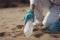 environmental pollution. Volunteer in protective gloves picks up a plastic bottle on the beach