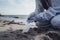 environmental pollution. Volunteer in protective gloves picks up a plastic bottle on the beach