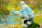 environmentalist on the shore of a forest lake takes water samples after an environmental