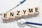 enzyme word written on wooden blocks and stethoscope on light white background