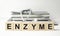 enzyme word written on wooden blocks and stethoscope on light white background