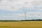 Eolian field and wind turbines farm, near yellow fllowers field, clouds blue sky