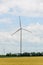 Eolian field and wind turbines farm, near yellow fllowers field, clouds blue sky