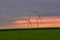 Eolian turbines used to produce green energy seen from a wheat field in the spring