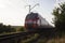 EP1M locomotive carrying a passenger train through a rural landscape in Russia.