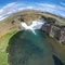 Epic aerial drone view flying over landscape of Hjalparfoss waterfall and lagoon