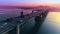 Epic aerial flight view of sunset in a big city on the river. The movement of cars on the bridge