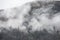 Epic dramatic landscape image of view from Elterwater across towards Langdale Pikes mountain range on foggy Winter morning