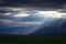 Epic, dramatic sunrays seeping through the clouds over the Andes Mountains in Mendoza, Argentina, on a dark, cloudy day