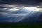 Epic, dramatic sunrays seeping through the clouds over the Andes Mountains in Mendoza, Argentina, on a dark, cloudy day.