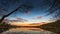 Epic red sunset sky above the lake and forest. Dramatic cloudscape. Symmetry reflections on the water, natural mirror