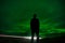 Epic silhouette by a man in front of the northern lights while a