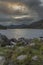 Epic stunning Autumn landscape image of Snowdon Massif viewed from shores of Llynnau Mymbyr at sunset with dramatic dark sky and