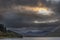 Epic stunning Autumn landscape image of Snowdon Massif viewed from shores of Llynnau Mymbyr at sunset with dramatic dark sky and