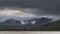 Epic stunning Autumn landscape image of Snowdon Massif viewed from shores of Llynnau Mymbyr at sunset with dramatic dark sky and