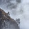 Epic Winter landscape image of view from Side Pike towards Langdale pikes with low level clouds on mountain tops and moody mist