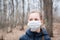 Epidemic covid-19. A girl in a medical mask walks alone in a deserted forest. Isolation and quarantine