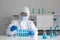 Epidemiological researcher in virus protective clothing look at  blue liquid chemicals in test tube. Coronavirus disease 2019