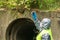 Epidemiologist in a protective suit and mask looks at a sample of the earth in a glass flask