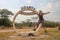 Equator in Queen Elizabeth National Park in Uganda and a joyful Caucasian European tourist girl jumping