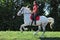 Equestrian model girl riding dressage horse in summer fields