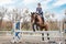 Equestrian sport. Show jumping competition. Young rider horseback girl jumping over an obstacle