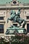 Equestrian statue with rampant horse in Vienna, with flowers in front and historic building behind.