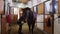 Equestrian - young woman brushing a brown horse in the stall