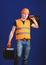 Equipped repairman concept. Worker, handyman, repairman, builder on calm face carries suitcase with tools on shoulder