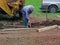 Erecting a Fence Man digging holes with spade and yellow digger