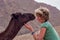 Erfoud, Morocco - Oct 17, 2019: A tourist girl cuddling up to a dromedary in the Sahara desert between Midelt and Erfoud