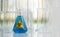 Erlenmeyer Flask contains blue liquid chemicals on white laboratory table