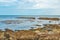 Eroded cracked brown rocks submerged in the still glassy vibrant blue sea