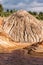 Eroded hill in a clay quarry with a forest in the background