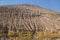 An eroded mountain with yellow leaves poplar trees.