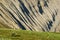 An eroded slope with a green lawn in the foreground