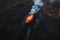 Erupted volcano and surroundings, boiling lava flowing, pull away drone shot