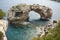 Es Pontas in Mallorca with boat anchored nearby in the Mediterranean sea. Majorca Sunrise with yacht and rock arch near Santanyi.