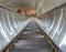 Escalator descending into dark tunnel of subway station