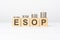 esop text written on wooden block with stacked coins on white background