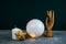 Esoteric still life with a ball of predictions , wooden female hand and candles on a concrete table against  black