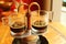 Espresso coffee trickling out from mini retro brewing pot into a pair of glass demitasse cups