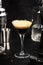 Espresso martini cocktail with vodka, coffee liqueur, syrup and ice, black background, bar tools