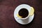 Espresso romano coffee with lemon in a white cup on a dark wooden table top view