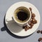 Espresso in a white mug on a white saucer next to coffee beans on a Gray background top view.