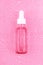 Essence moisturizing serum in glass bottle with white pipette on pink background with water drops. Hyaluronic acid.